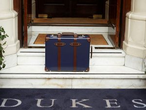 A blue, traditional suitcase outside of DUKES London in Mayfair
